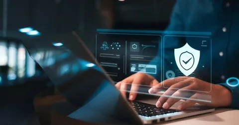Security consulting services concept with hands typing on a laptop beneath a glowing digital interface showing a shield and checkmark, representing data protection and confidence.
